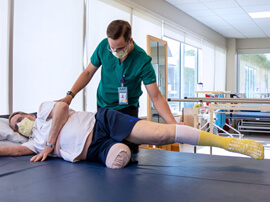 Therapist wearing green scrubs working with a male amputee patient.